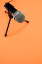 Vertical shot of a microphone on a small stand, on an orange surface