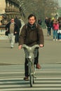 Vertical shot of a middle-aged male with a jacket cycling on a road in Paris, France