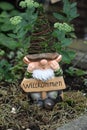 Vertical shot of a miniature gnome with a welcome sign in a green garden