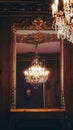 Vertical shot of the mirror with a gold frame reflects the beauty of magnificent chandeliers Royalty Free Stock Photo