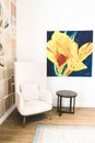 Vertical shot of a modern armchair in a bright room with a floral painting and book art installation