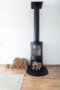 Vertical shot of a modern chimney with firewoods in the room with a white wall Royalty Free Stock Photo