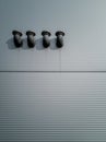Vertical shot of a modern construction of four black tubes hanging on a white wall Royalty Free Stock Photo