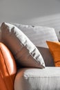 vertical shot of a modern couch and several grey and orange pillows on it