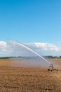 Vertical shot of a modern farm water sprinkler irrigation system watering field during dry weather