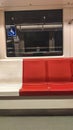 Vertical shot of modern seats in the train with a reflection of a human with a mask in the window