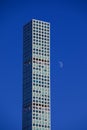 Vertical shot of the moon rising near a skyscraper in New York City