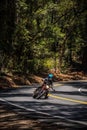 Vertical shot of a motorcyclist driving with one leg out on rural mountain road