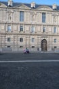 Vertical shot of a motorcyclist passing by a side door of the Louvre in Paris, France