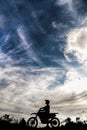 Vertical shot of a motorcyclist silhouette on a bright cloudy sky background Royalty Free Stock Photo