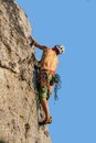 Vertical shot of a mountain climber climbing the rocks using his climbing equipment