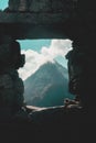 Vertical shot of a mountain with a peak of clouds as seen from the ruined stone wall opening Royalty Free Stock Photo