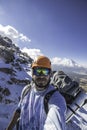 Vertical shot of a mountaineer taking a selfie with a camping backpack and a landscape full of snow and rocks with an active