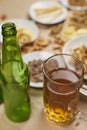 Vertical shot of a mug and bottle of beer next to snacks on the table Royalty Free Stock Photo