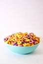 Vertical shot of multicolored fruity cereals in a blue bowl isolated on white background