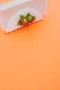 Vertical shot of a napkin holder with strawberry detail on orange background