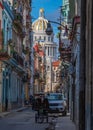 Vertical shot of a narrow street with traditional buildings and Havana capitol