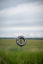 Vertical shot of a natural field and a car wheel sign has a writing no hunting and no trespassing