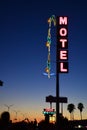 Vertical shot of a neon motel sign on the background of the sunset in the sky Royalty Free Stock Photo