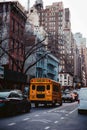 Vertical shot of New York traffic with a school bus in it surrounded by skyscrapers