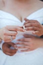 Vertical shot of a newly married couple embracing and putting rings on their fingers