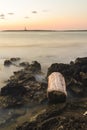 Vertical shot of an ocean with the view of rocks and a lighthouse. Foggy waves in Menorca Spain