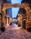 Vertical shot of an old alley with brick buildings decorated with Christmas lights Royalty Free Stock Photo