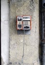 Vertical shot of an old broken public telephone attached to a wall