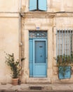 Vertical shot of an old building facade with a blue entrance door and wooden window shutters Royalty Free Stock Photo