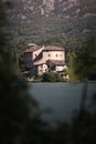 Vertical shot of an old castle surrounded by evergreen mountains with a lake in the foreground Royalty Free Stock Photo