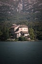 Vertical shot of an old castle surrounded by evergreen mountains with a lake in the foreground Royalty Free Stock Photo