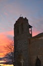 Vertical shot of an old church with a damaged bell tower with the sun setting in the background Royalty Free Stock Photo