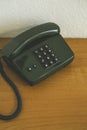 Vertical shot of an old dark green telephone on a wooden surface Royalty Free Stock Photo