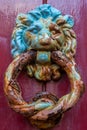 Vertical shot of an old lion brass door knocker on a red wooden door Royalty Free Stock Photo