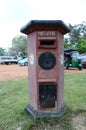 Vertical shot of an old red post box near a green sidewalk