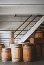 Vertical shot of old rustic wine barrels under the white wooden staircase in the basement Royalty Free Stock Photo