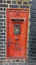 Vertical shot of an old rusty damaged weathered Victorian wall mounted postbox Royalty Free Stock Photo