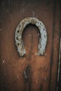 Vertical shot of an old rusty horseshoe hanging on a wooden door