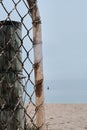 Vertical shot of an old rusty pipe and metal mesh gate on a beach