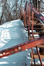 Vertical shot of an old rusty stairway in a snow-covered park Royalty Free Stock Photo