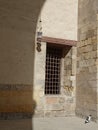 Vertical shot of old stone wall with grunge net metal windows with sunlight Royalty Free Stock Photo