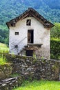 Vertical shot of an old white house with a wooden roof isolated in a green forest Royalty Free Stock Photo