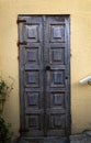 Vertical shot of an old wooden door of a building with light yellow walls Royalty Free Stock Photo