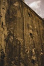 Vertical shot of an old, worn-out factory`s wall with small square windows visible Royalty Free Stock Photo