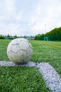 Vertical shot of an old worn-out soccer ball on a field with artificial grass Royalty Free Stock Photo