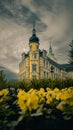Vertical shot of Oldenburg Palace surrounded by grass and flowers against cloudy sky in Germany