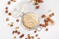 Vertical shot of an open jar of oatmeal on white with hazelnuts and almond Royalty Free Stock Photo