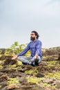 vertical shot ot Young beard man with eyes closed doing meditation or yoga on top of hill - concept of self caring Royalty Free Stock Photo