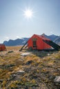 Vertical shot of Owl River emergency shelter in remote arctic wilderness with a backpack in front of it . Sunny day in