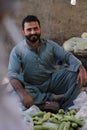 Vertical shot of a Pakistani male with a beard in a market selling fruits in a shalwar kameez